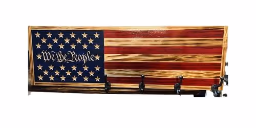 Wooden coat rack painted like the American flag with the words 'We the People' on the blue field.