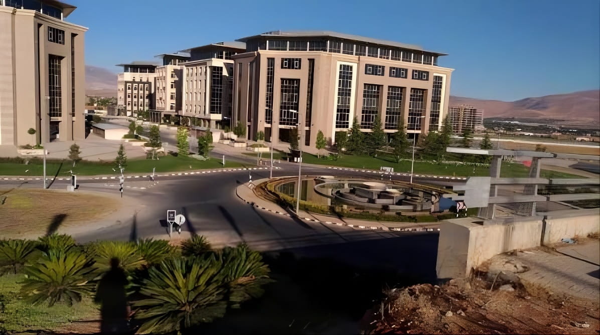 Office buildings beside a roundabout at The Eighth Gate development, Yaafour, Rural Damascus, with hills in the background