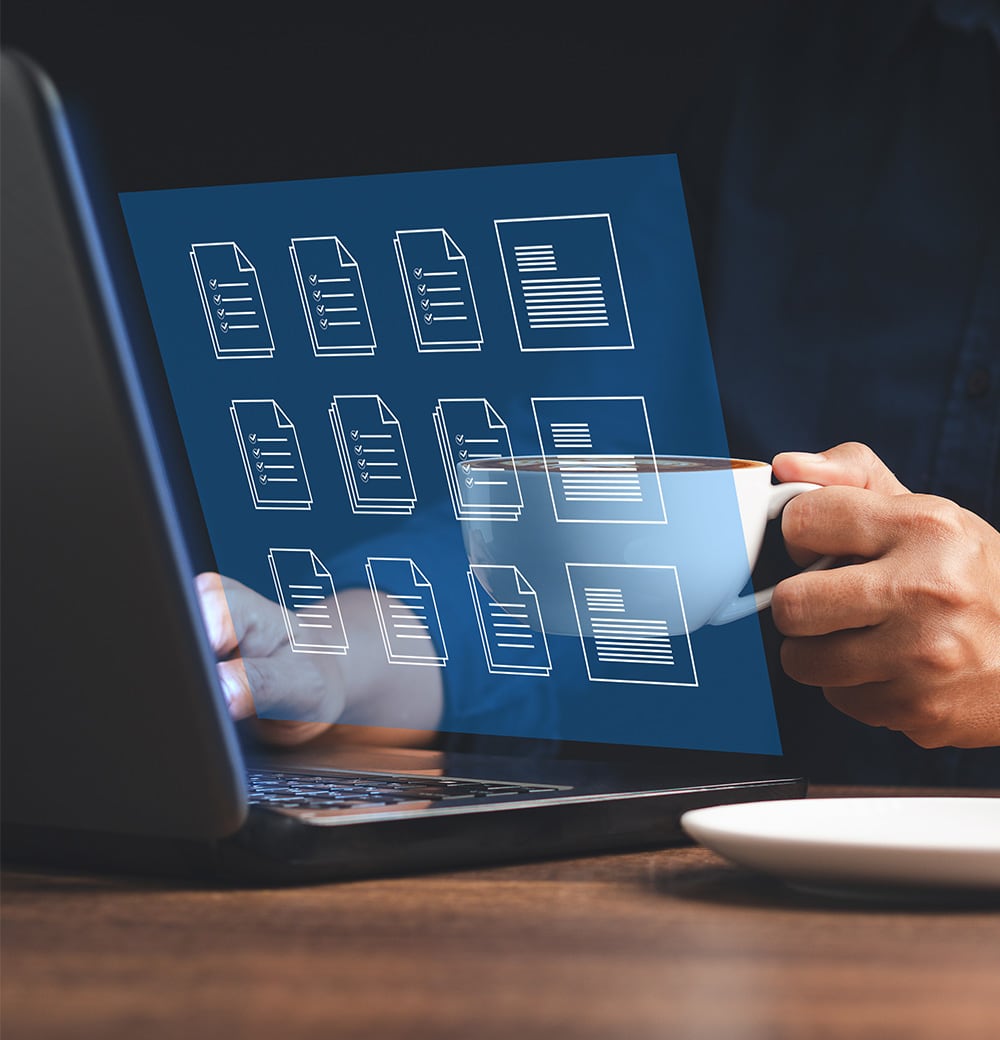 Person hält eine weiße Tasse Kaffee vor einem Laptop, auf dem digitale Dokumentensymbole eingeblendet sind.