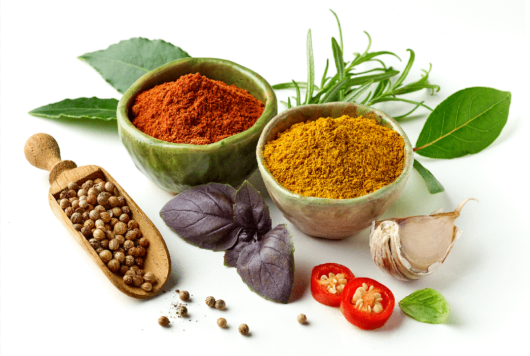 Assortment of colorful spices, herbs, fruits, mushrooms, powders in bowls, olive oil, honey dripping, and red capsules arranged on a transparent background.