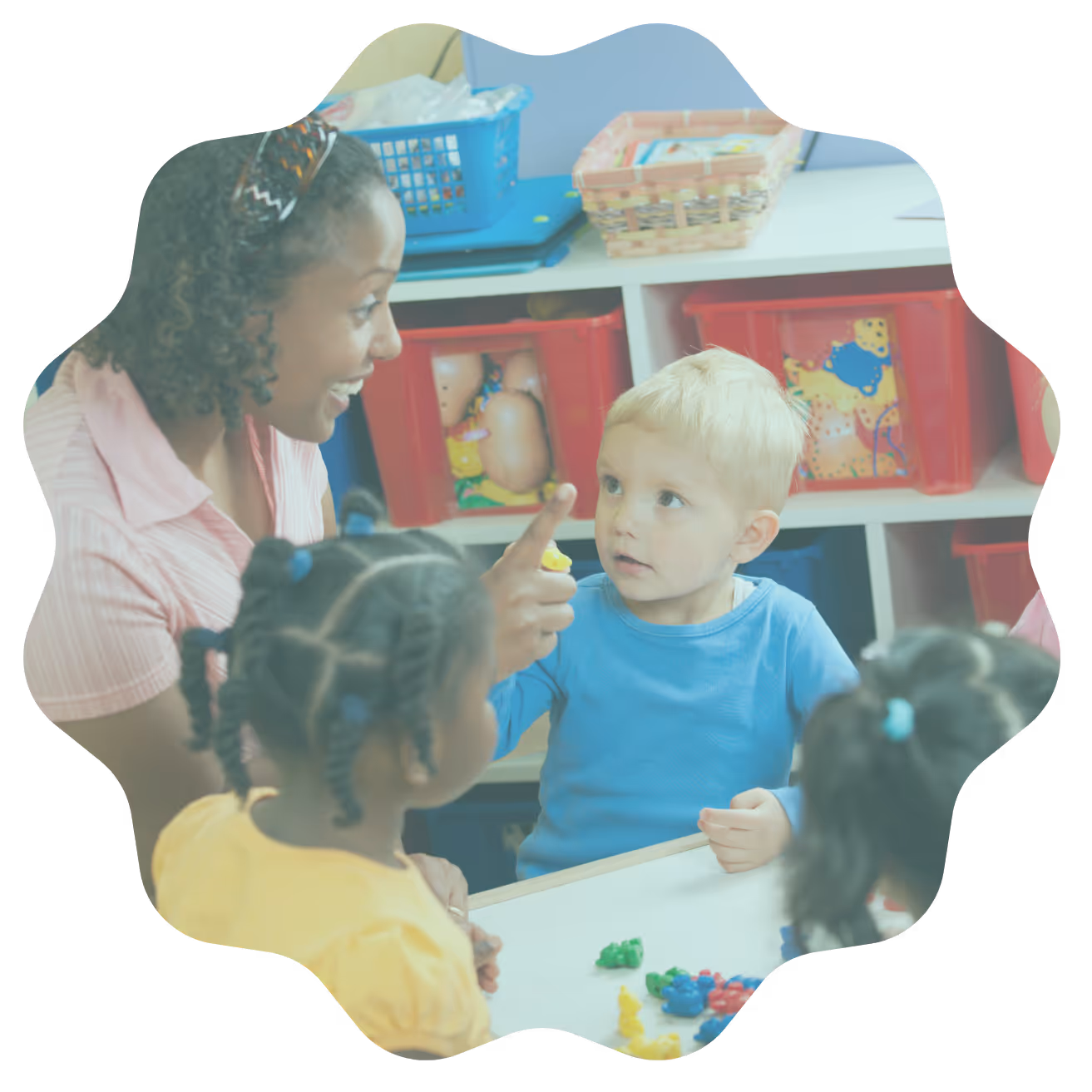 Teacher engaging with young children at a table with colorful toys in a classroom setting.