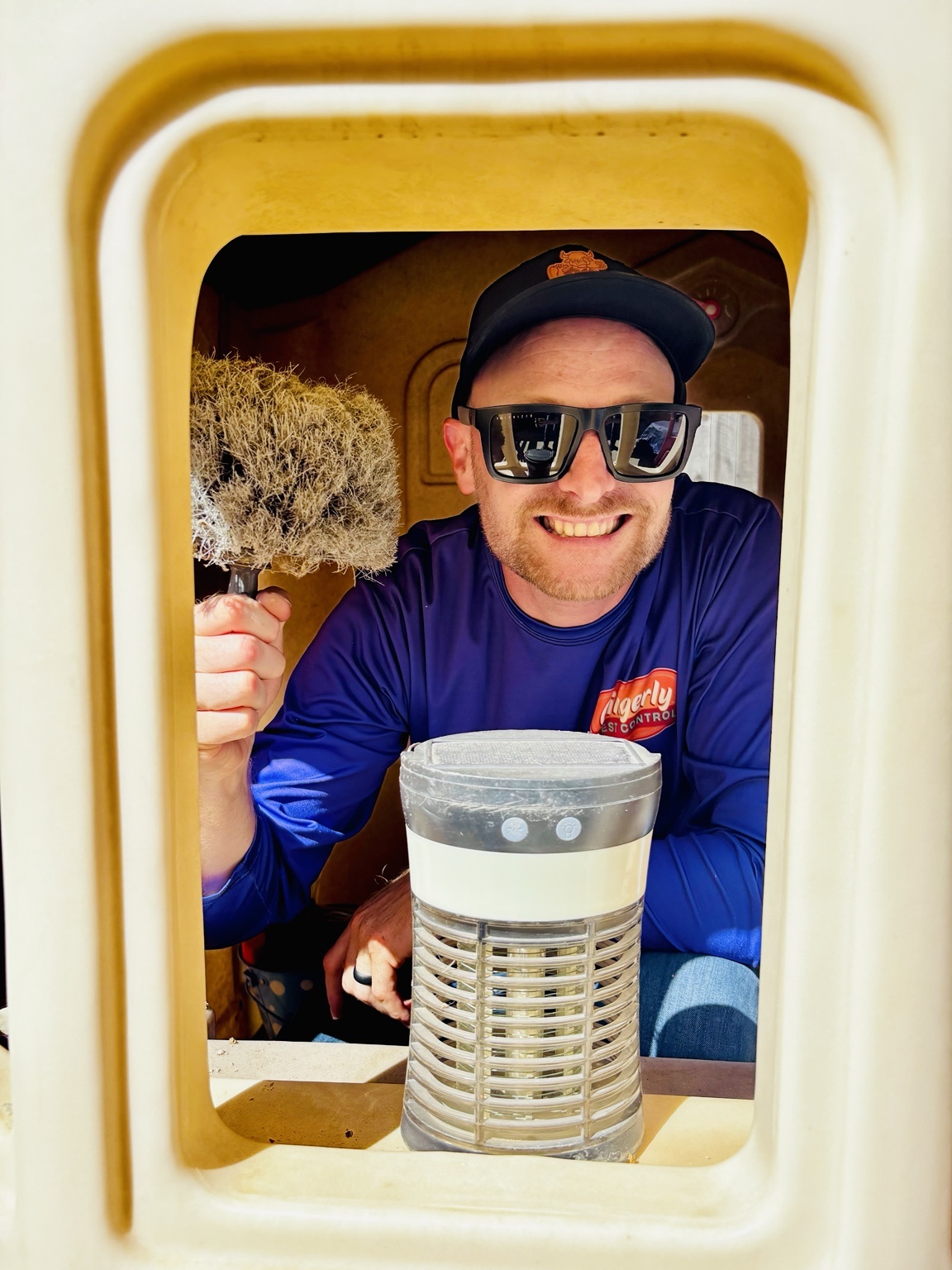 Gingerly Pest Control owner smiling from inside a children's playhouse during a spider check