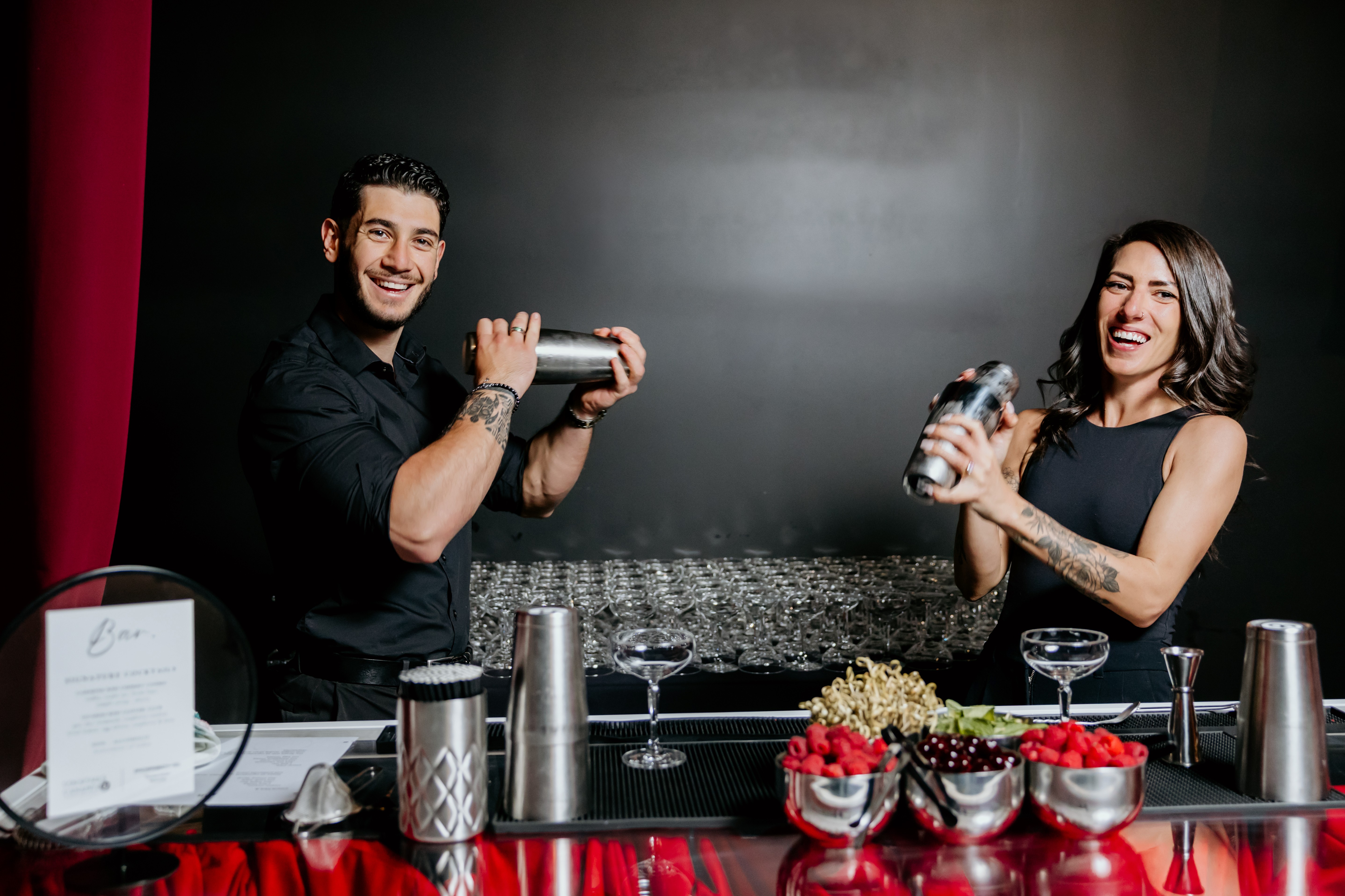 Bartenders behind the bar are making cocktails for the event.