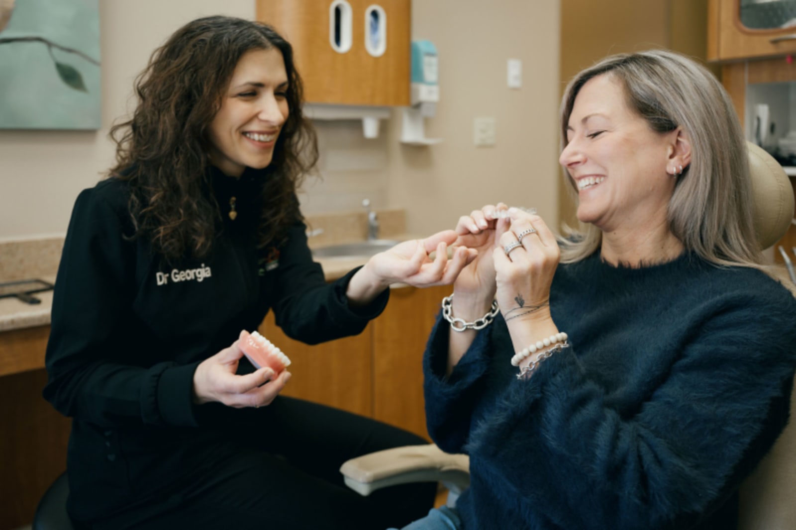 Dentist showing tooth-colored filling sample to patient during consultation