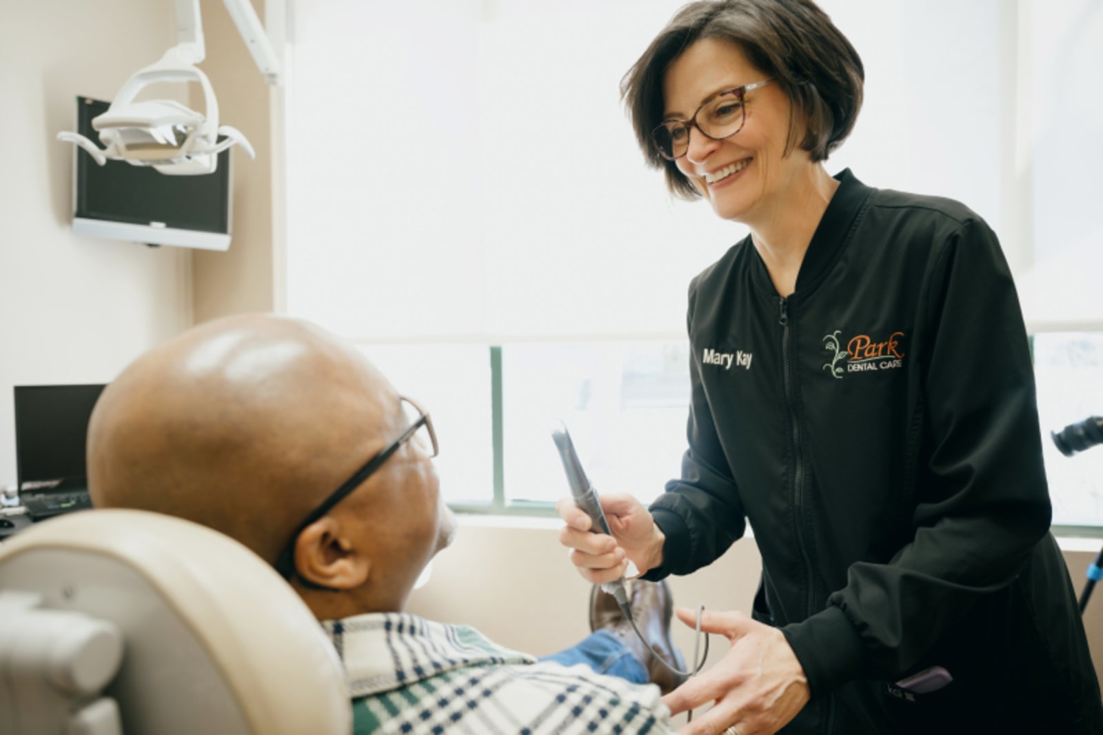 Dentist explaining dental implant procedure to patient in treatment room