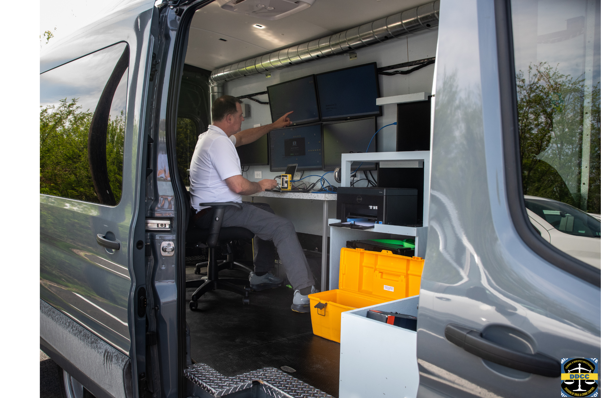 A man in a mobile investigation unit examines a computer sceen.