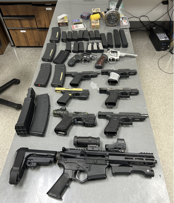 Various seized firearms lay spread out on a table.