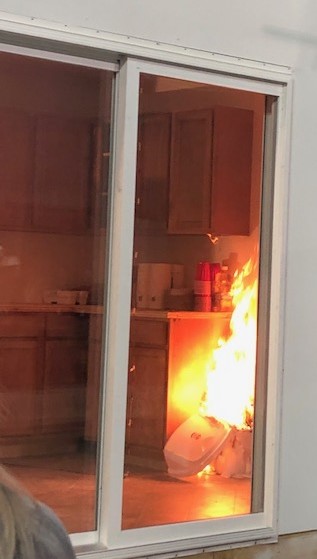Fire burning through the window of a building.