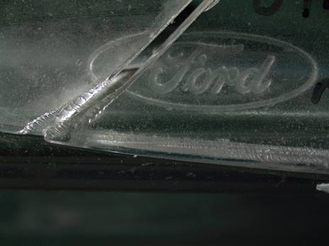Two pieces of an automobile headlight aligned, with a manufacturer emblem continuing across the break.