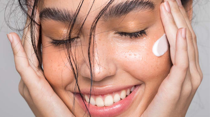 A person smiles gently with their eyes closed, resting their hand on their face. The close-up captures a feeling of warmth and connection.