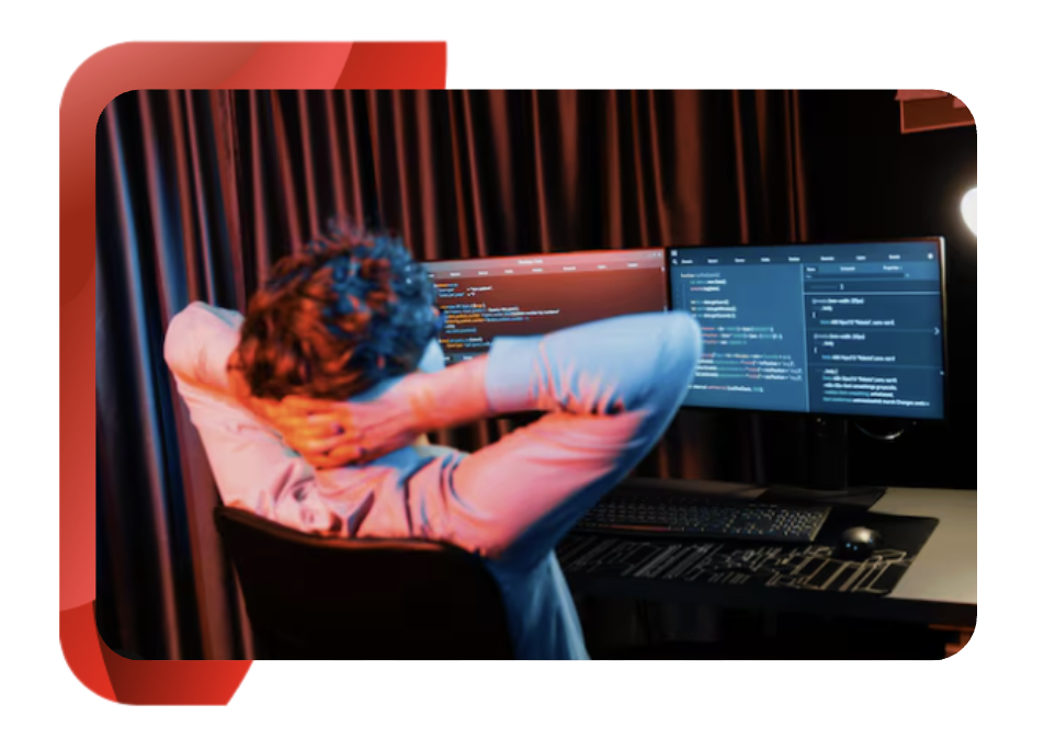 A person in a relaxed position, sitting in front of a computer that displays code