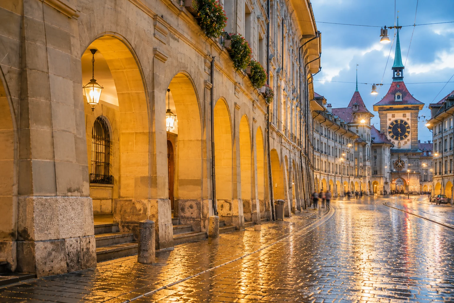 Arcades en grès de Berne au crépuscule, avec pavés mouillés, éclairage chaleureux et silhouettes floutées au loin.