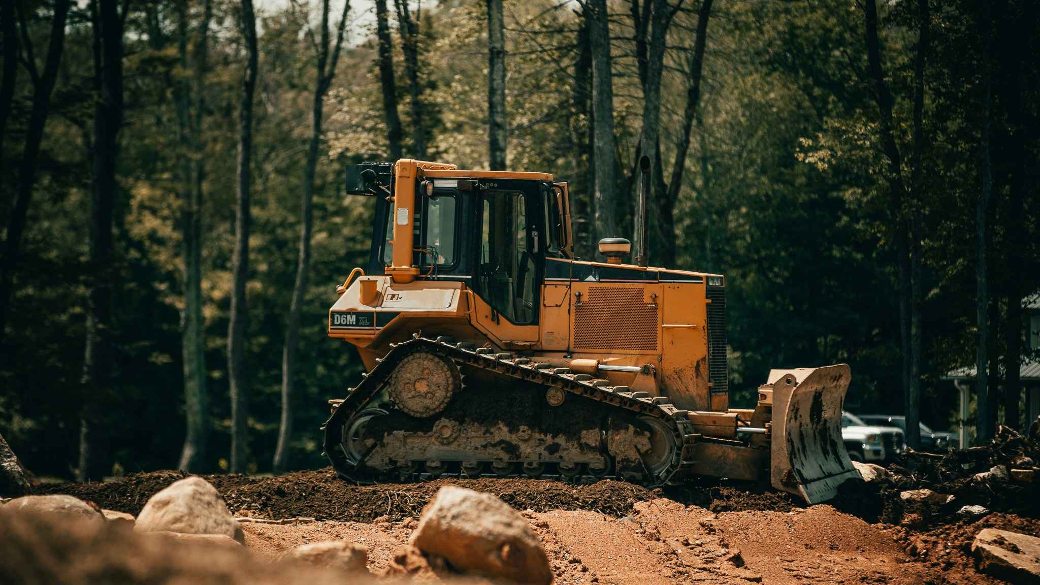 A bulldozer sits in the middle of a development site in a forest.