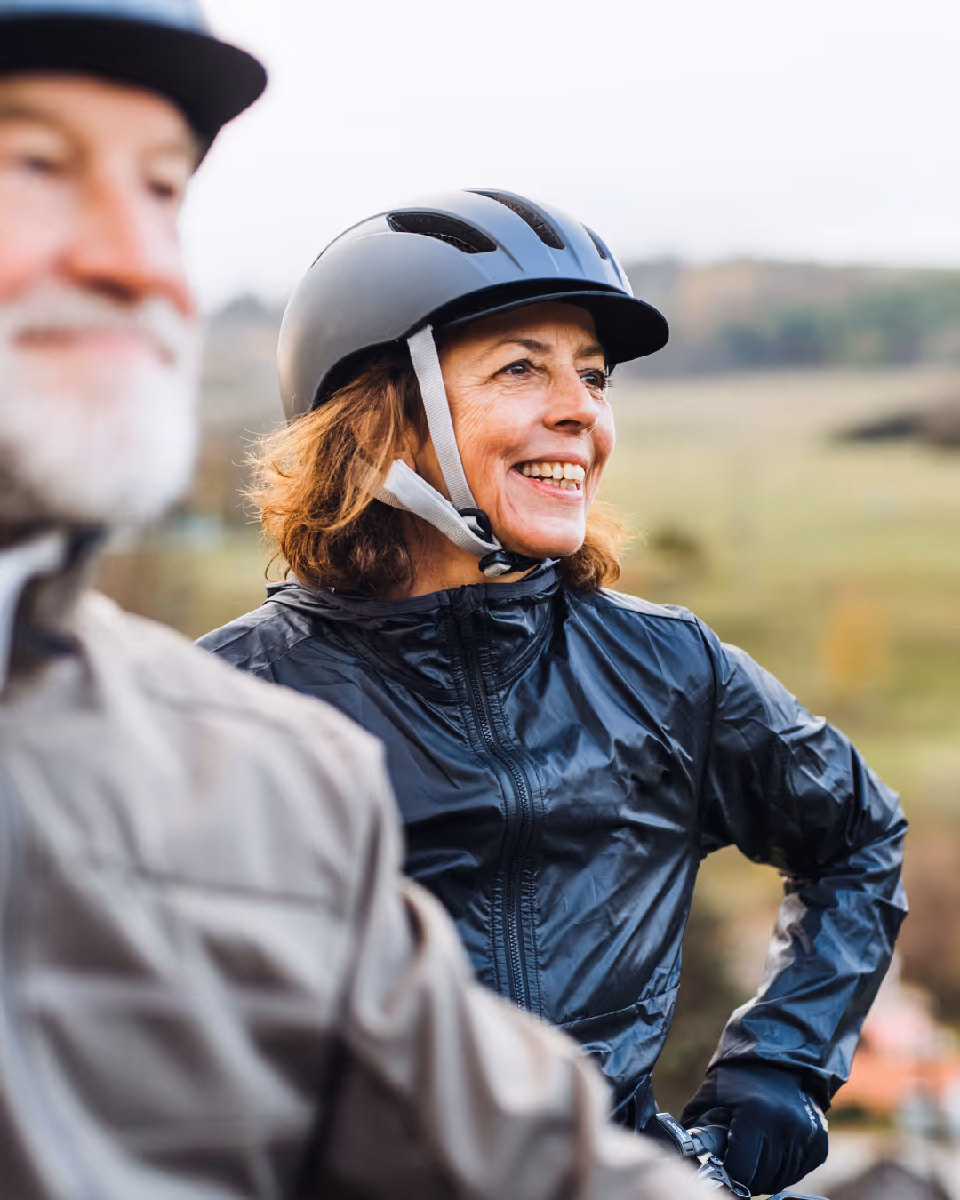 Woman smiling while cycling outdoors, representing an active lifestyle supported by Belle's telehealth wellness programs