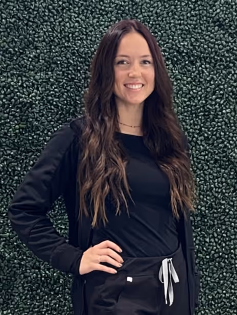 Smiling woman with long wavy blonde hair wearing clear-framed glasses and a blue top.