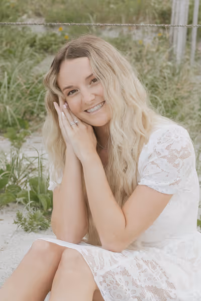 Smiling woman with long curly blonde hair wearing clear-framed glasses and a blue top.