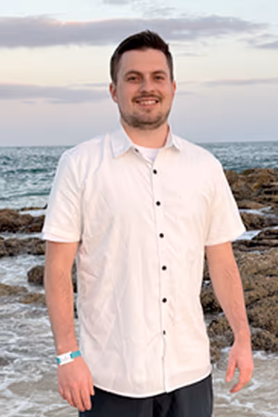 Smiling woman with long curly blonde hair wearing clear-framed glasses and a blue top.