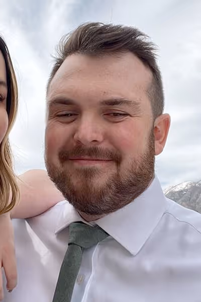 Smiling woman with long curly blonde hair wearing clear-framed glasses and a blue top.