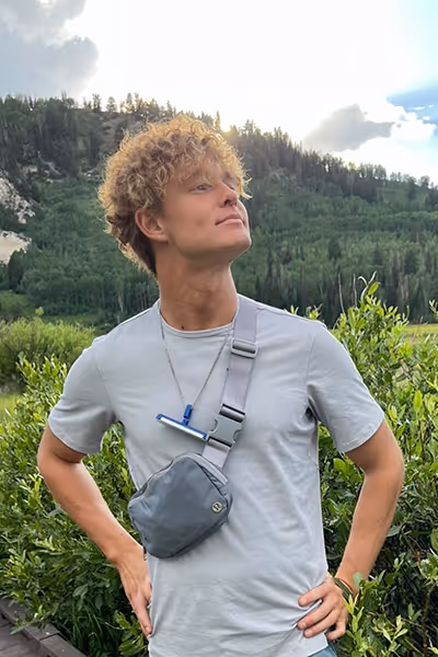 Smiling woman with long curly blonde hair wearing clear-framed glasses and a blue top.