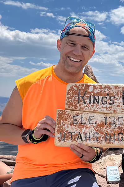 Smiling woman with long curly blonde hair wearing clear-framed glasses and a blue top.