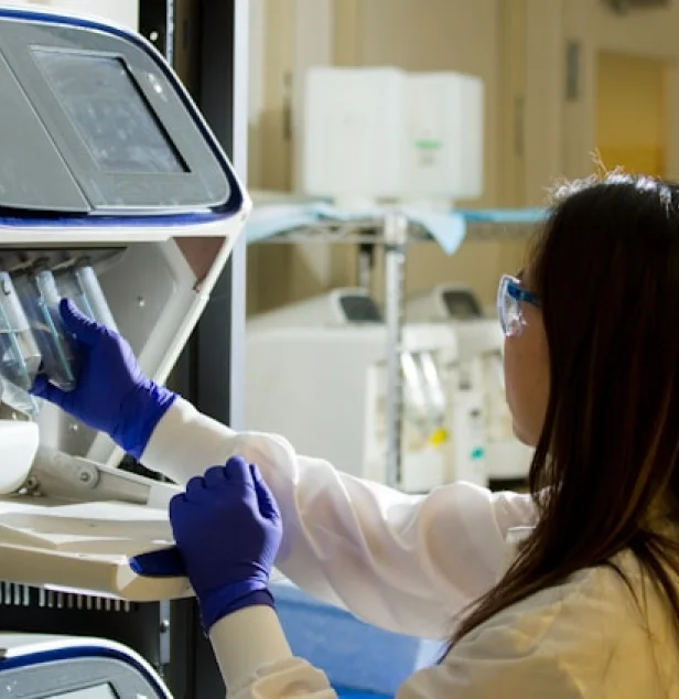 Chercheuse en blouse blanche et gants bleus utilisant un appareil de laboratoire LABELIANS pour insérer des tubes d'échantillons.