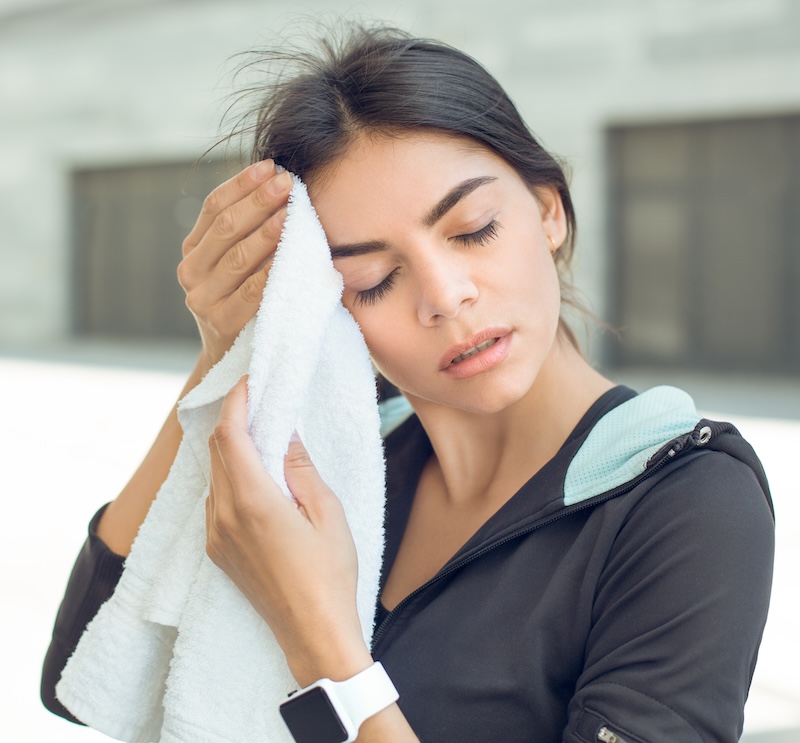 Woman wiping sweat off with towel. 