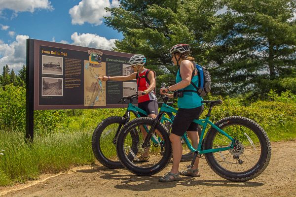 Cyclists reading the From Rail to Trail sign on the Old Rail Trail