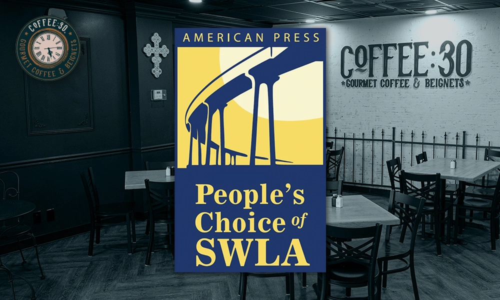 Interior of Coffee:30 cafe with black chairs and tables, a wall clock, a decorative cross, and a sign reading 'Coffee:30 Gourmet Coffee & Beignets'; overlayed graphic states 'American Press People's Choice of SWLA' with a bridge illustration.