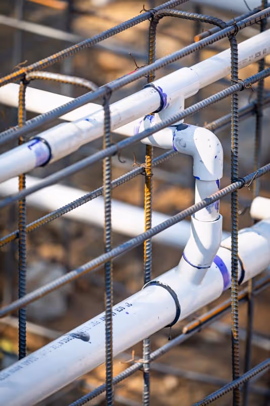 White pipes connected with blue joints on metal rebar construction frame