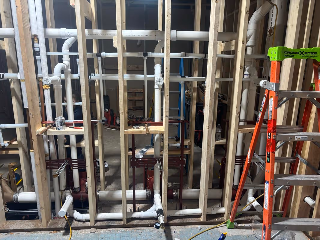 Plumbing pipes and wooden framing during construction with ladders