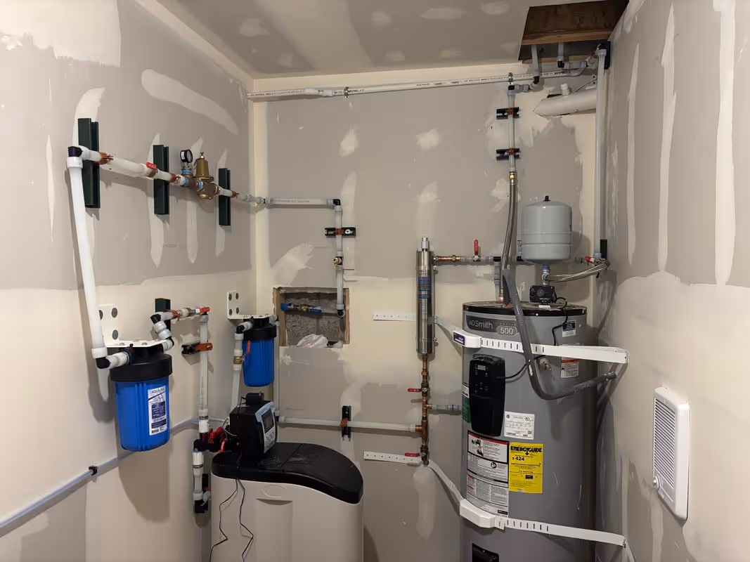 Water filtration and water heater system in utility room with pipes and equipment