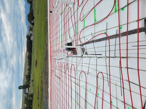 Radiant heating pipes laid out on white mesh before concrete floor pouring