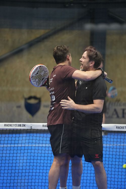 Female padel player returning a volley on a blue turf court