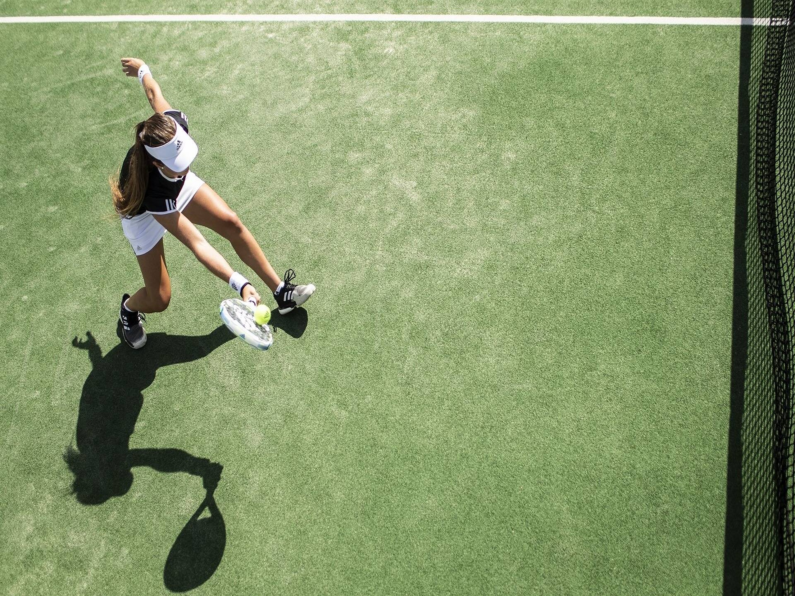 Padel balls placed on and next to cups on a blue turf court