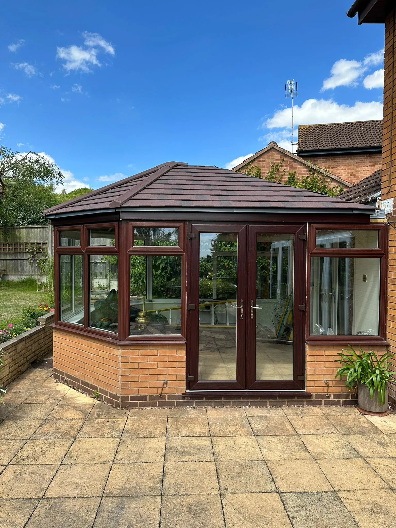Rosewood uPVC conservatory with French doors and a tiled roof on a paved patio