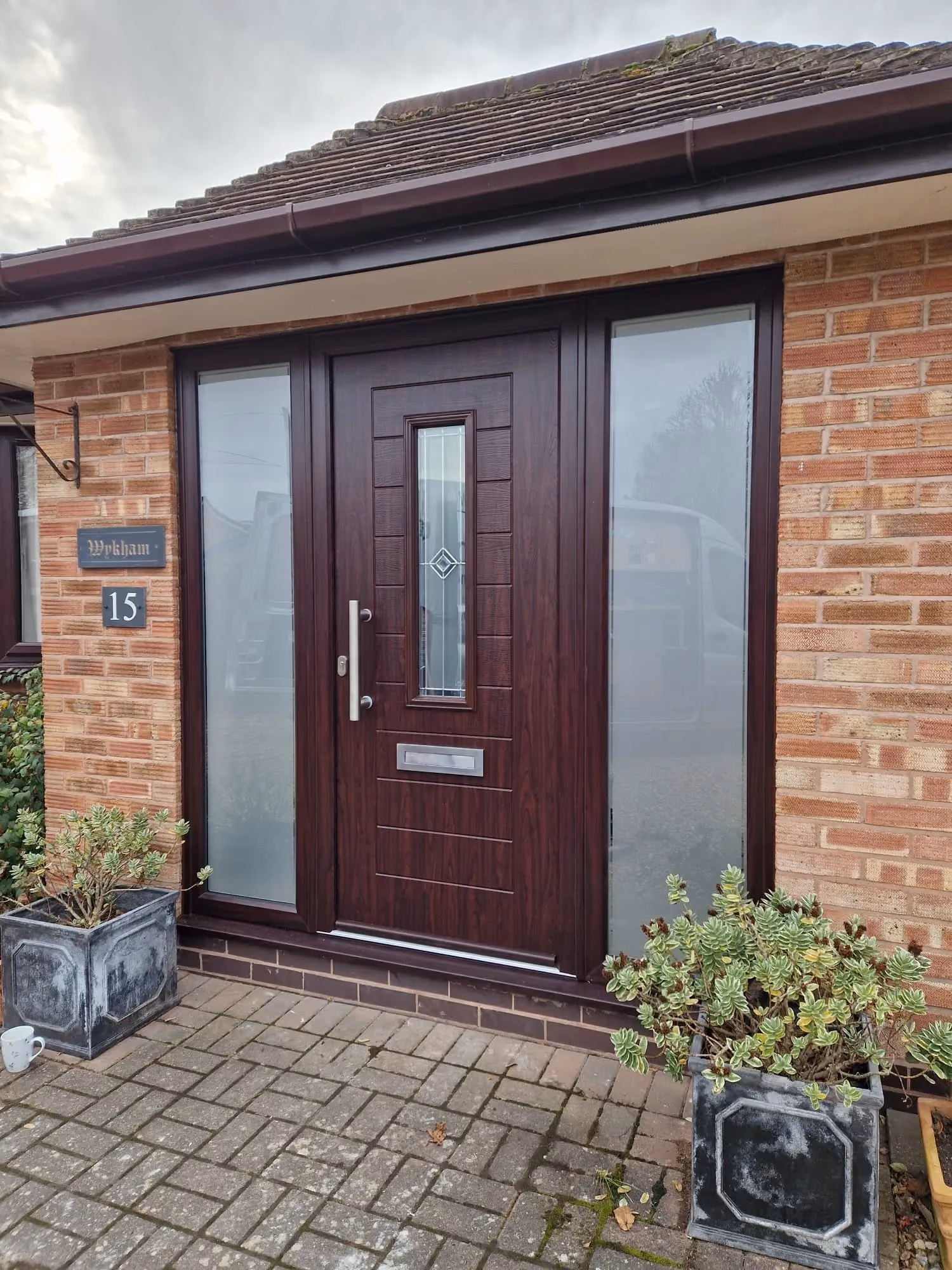 Front entrance of a house featuring a luxury front door with vertical glass panel and silver door handle.