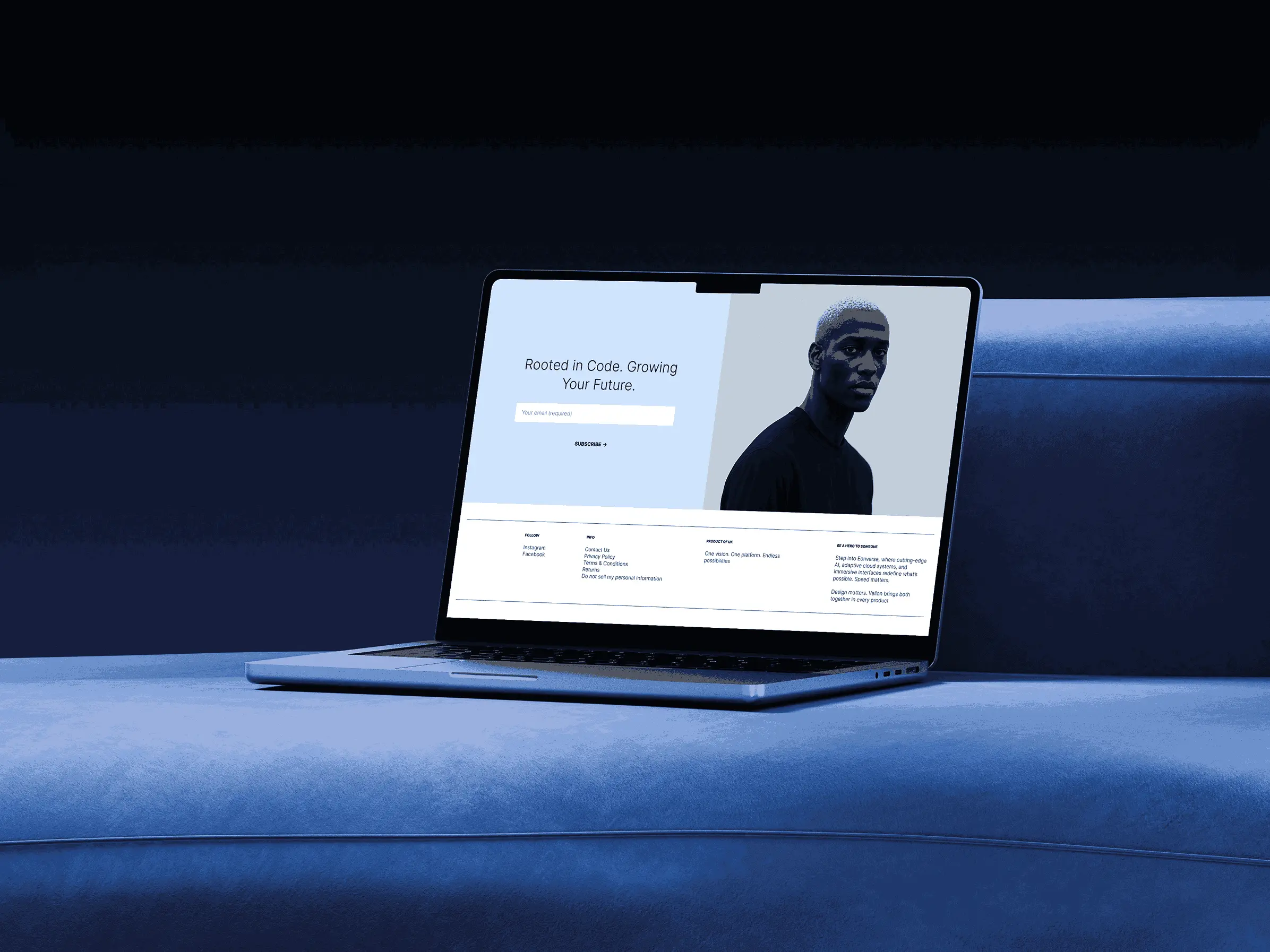 MacBook on blue bench in dark room displaying digital design