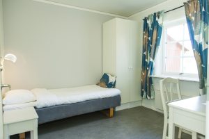 Internatrum med bäddad säng och sängbord