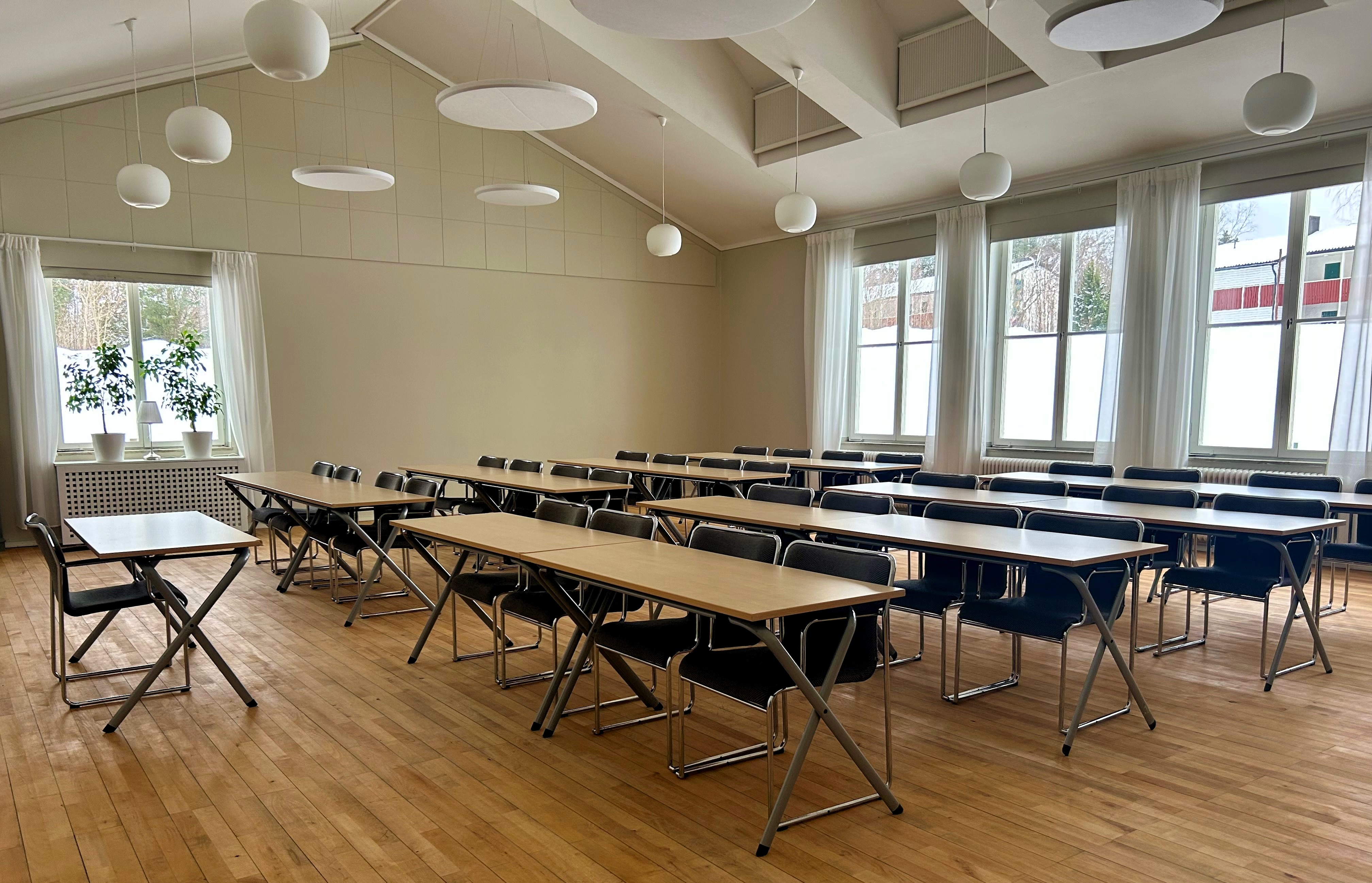 Bord och stolar möblerat för konferens i ljus lokal.