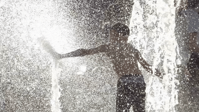Child playing in water spray fountain