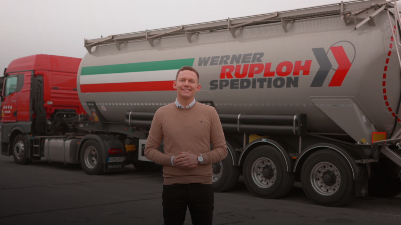 Mann steht vor einem LKW-Siloauflieger der Werner Ruploh Spedition auf einem Betriebshof.
