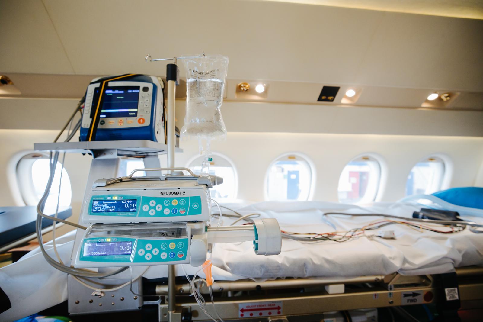 Un lit médicalisé avec des moniteurs et une perfusion à bord d'un avion aménagé pour les vols médicalisés.