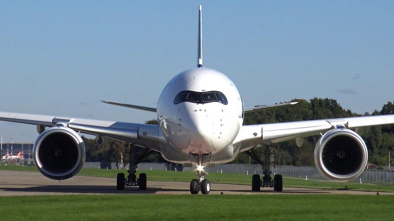 Vue frontale d'un avion commercial blanc sur une piste d'aéroport avec un ciel bleu clair.