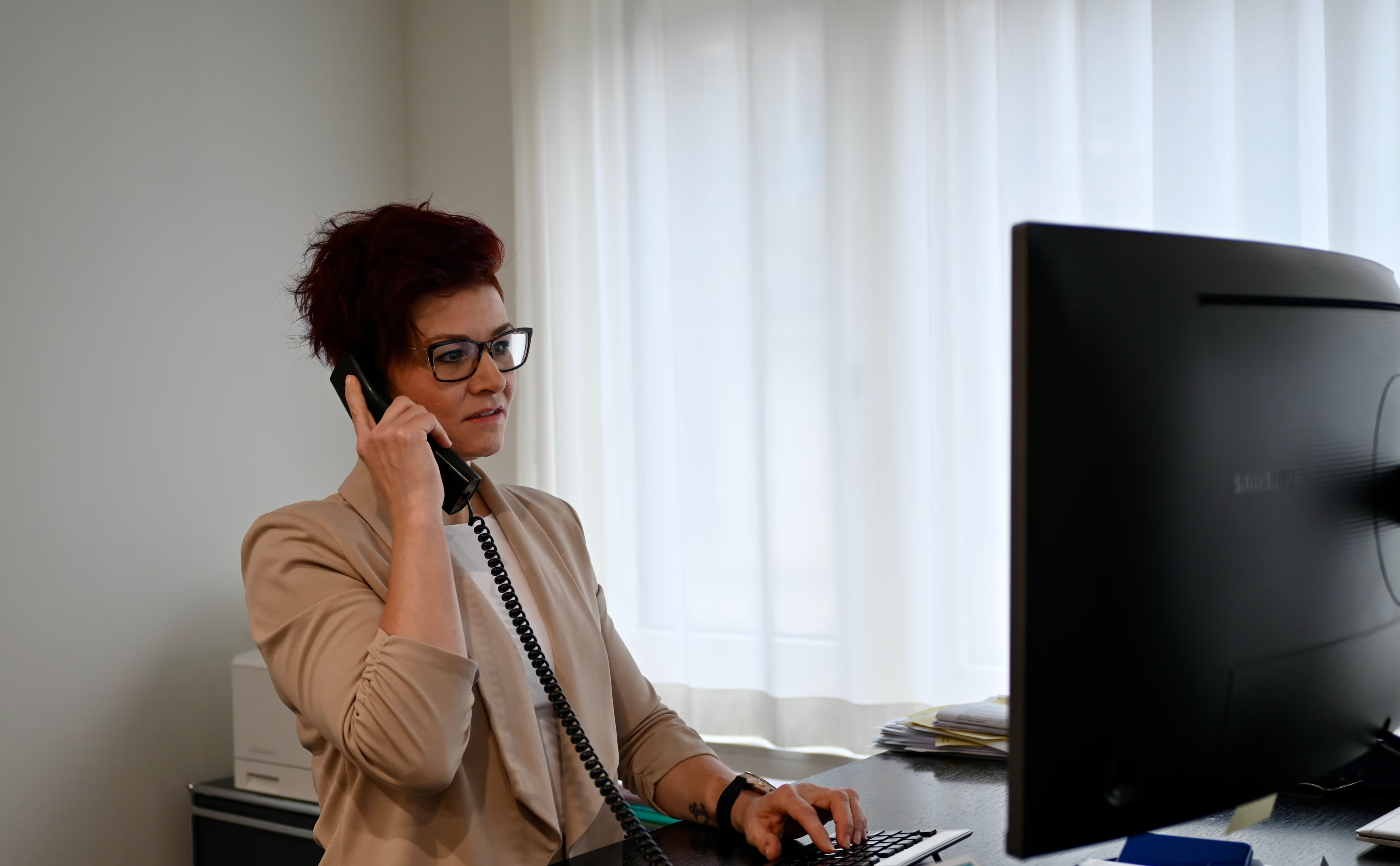 Eine Dame sitzt am Arbeitsplatz und telefoniert.
