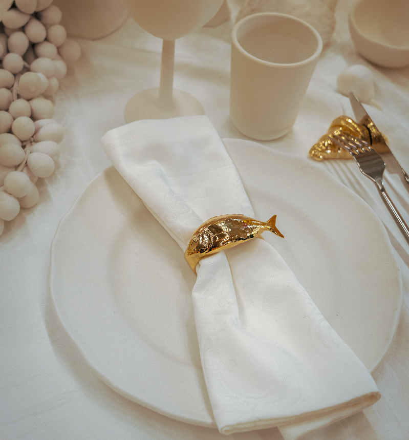 Luxury tableware made in France. Golden napkin ring in the shape of a fish, brass napkin ring, bronze napkin ring, luxury table setting and tablescaping. Perfect for luxury tables, hospitality flatware, design or decor objects for the table. 
