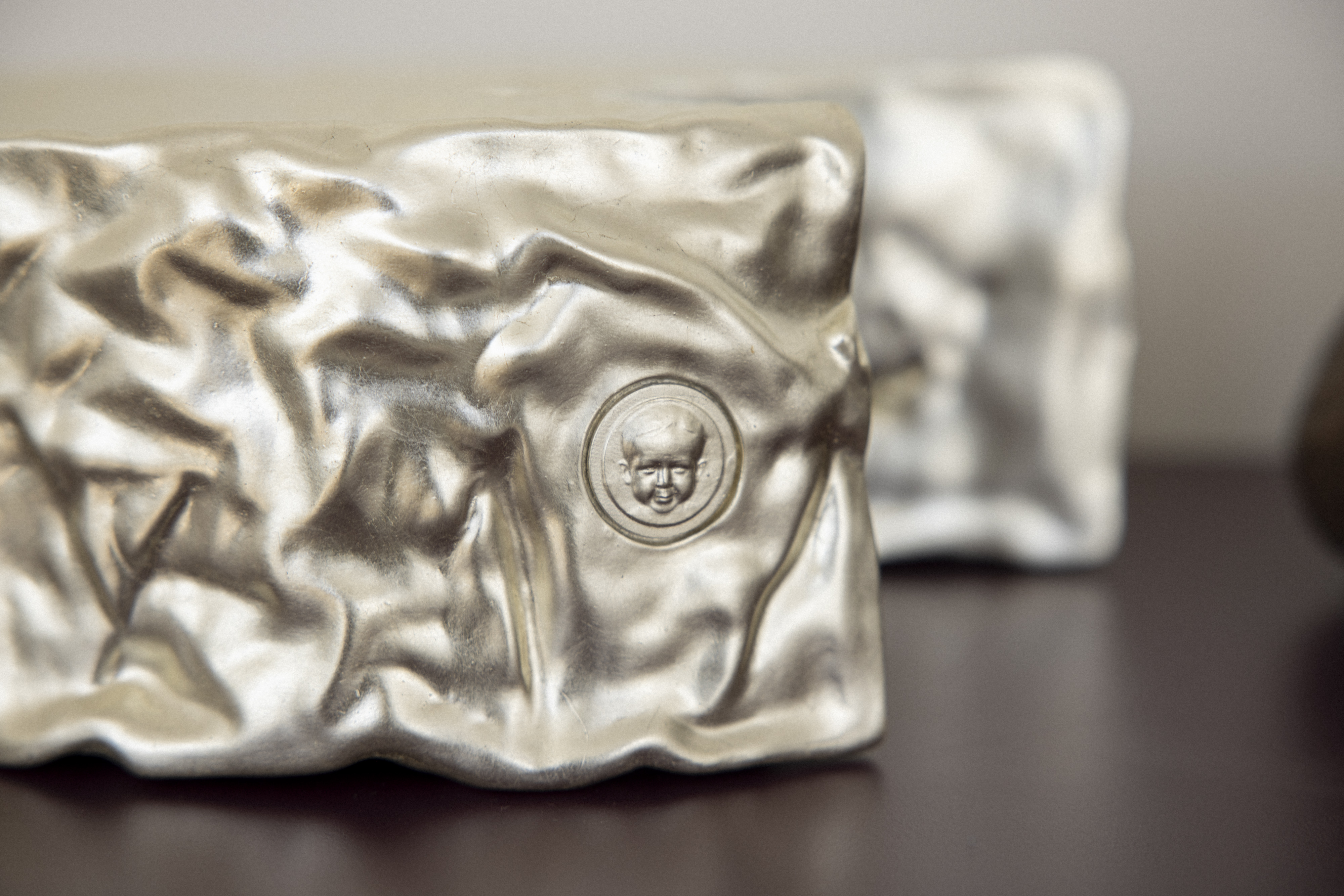 A contemporary centerpiece finished with white gold leaf, in the shape of a Camembert. in the closeup you can see the emblem, the face of the grand son standing for Ferdie.