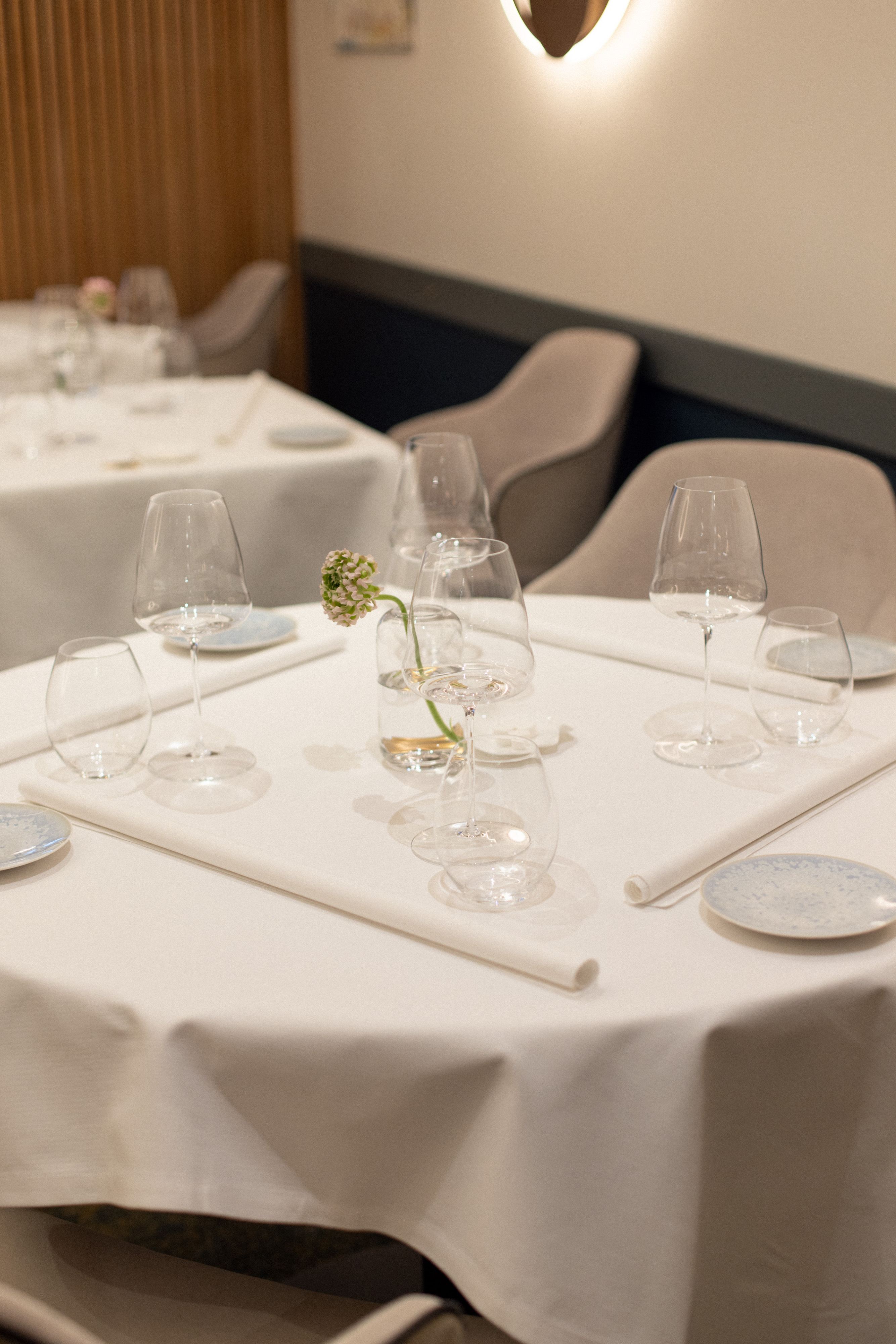 Détail d’une table de restaurant gastronomique de luxe avec serviette roulée, vaisselle contemporaine et objets décoratifs inspirés de l’art de la table français.