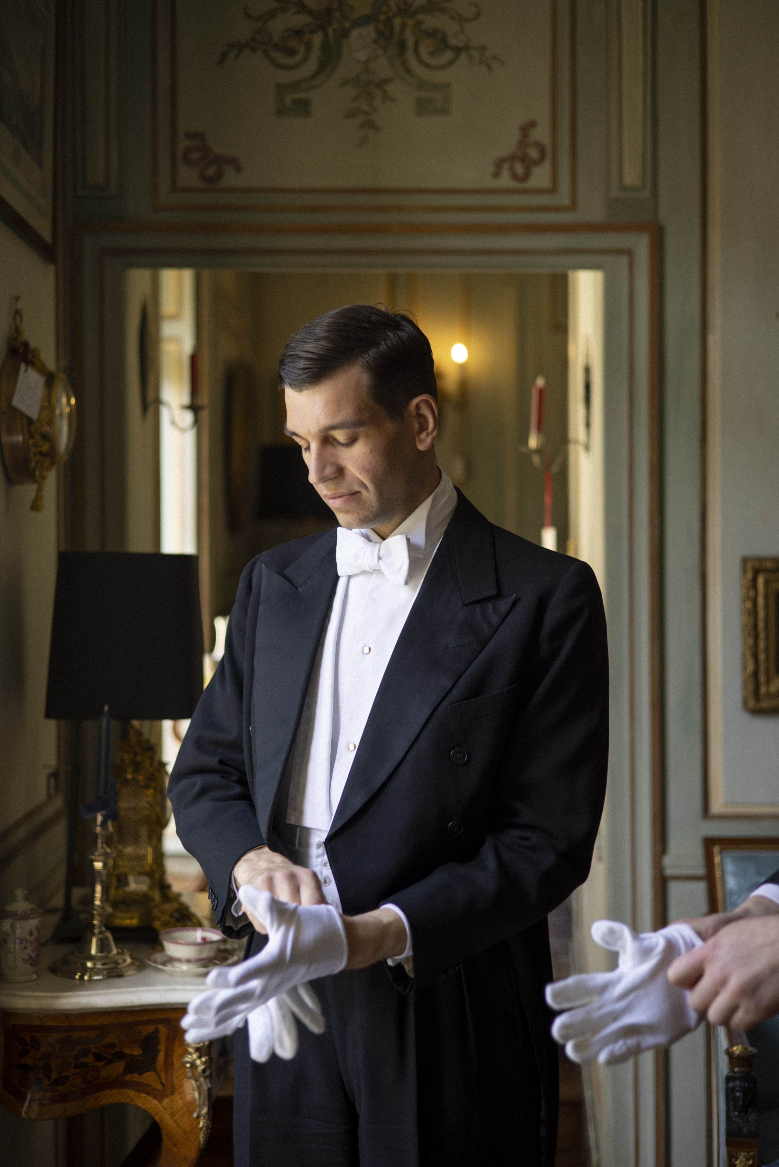 Majordome préparant une table raffinée avec argenterie et porcelaine dans une demeure historique à Versailles, illustrant l’art de recevoir à la française.