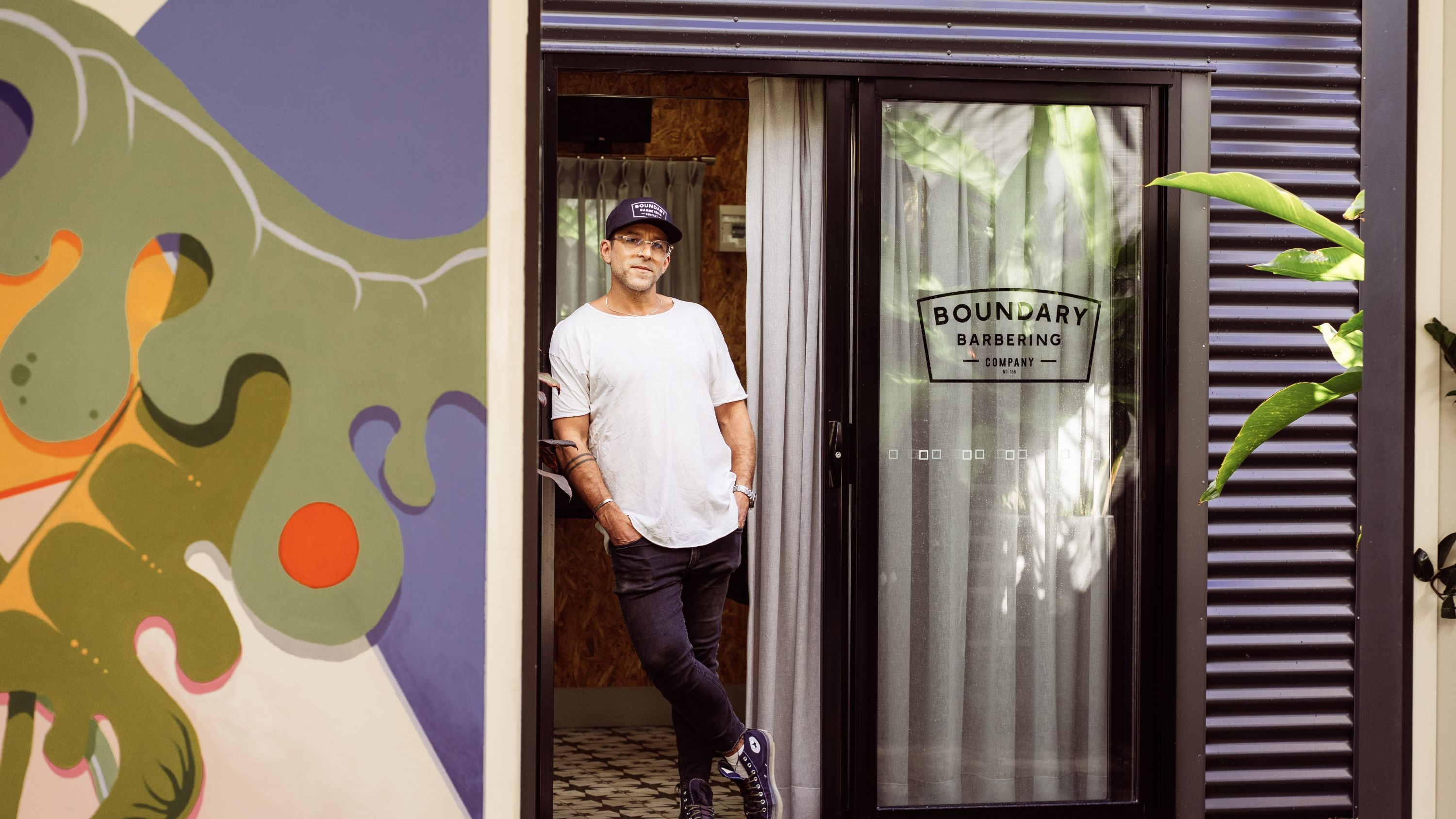 Award Winning Barber, Jon Miller, stands in the doorway of his barbershop Boundary Street Barbering