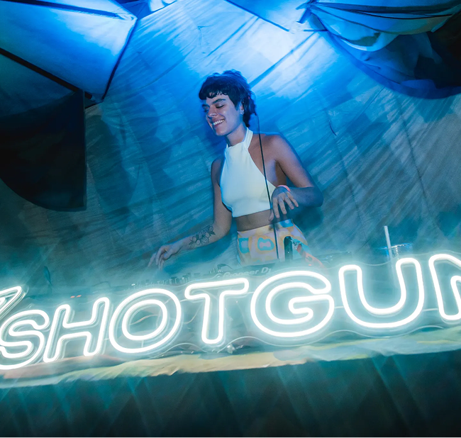A woman standing in front of a neon sign.